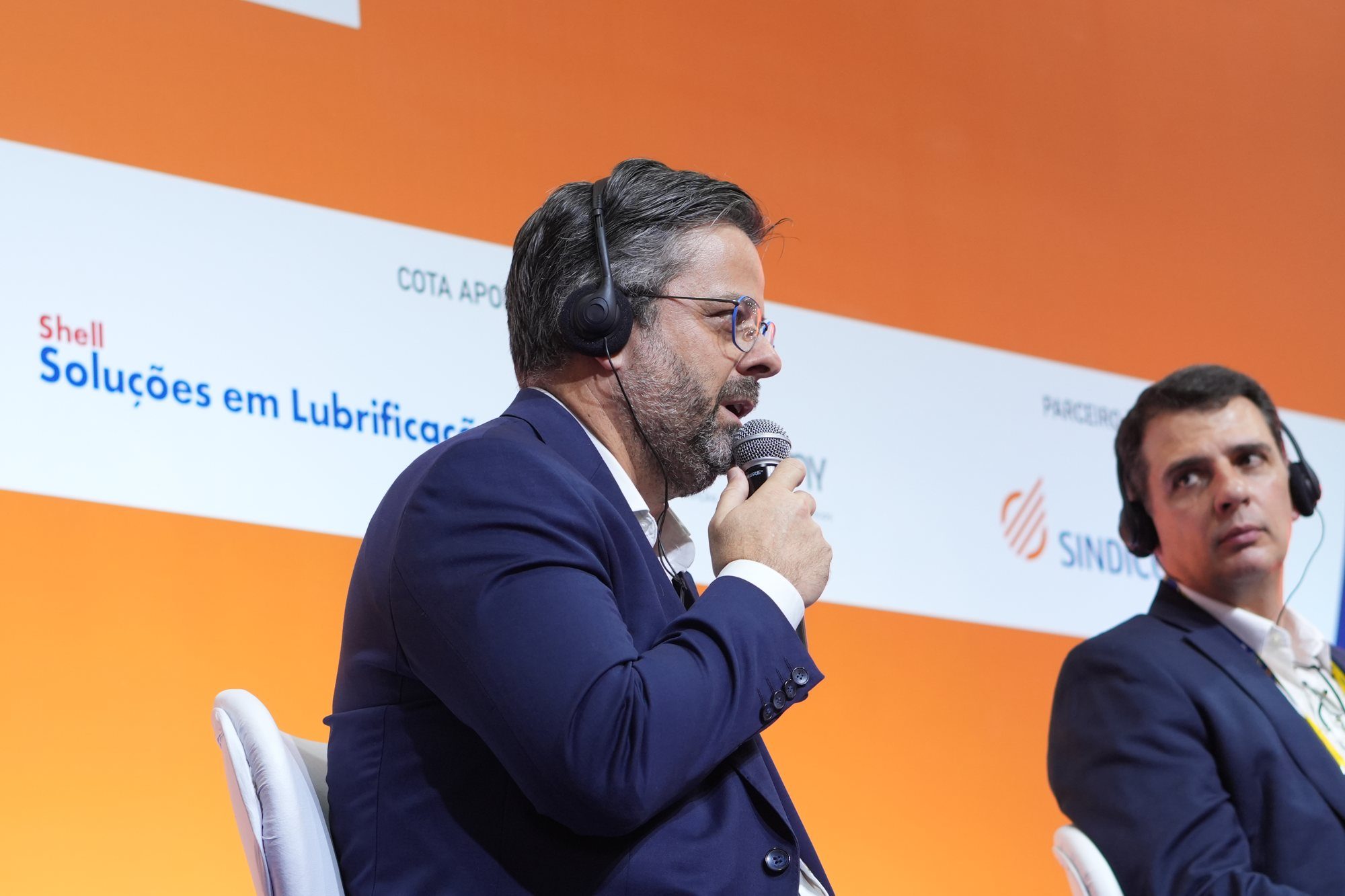 Palestrante em painel, com o logo Shell ao fundo