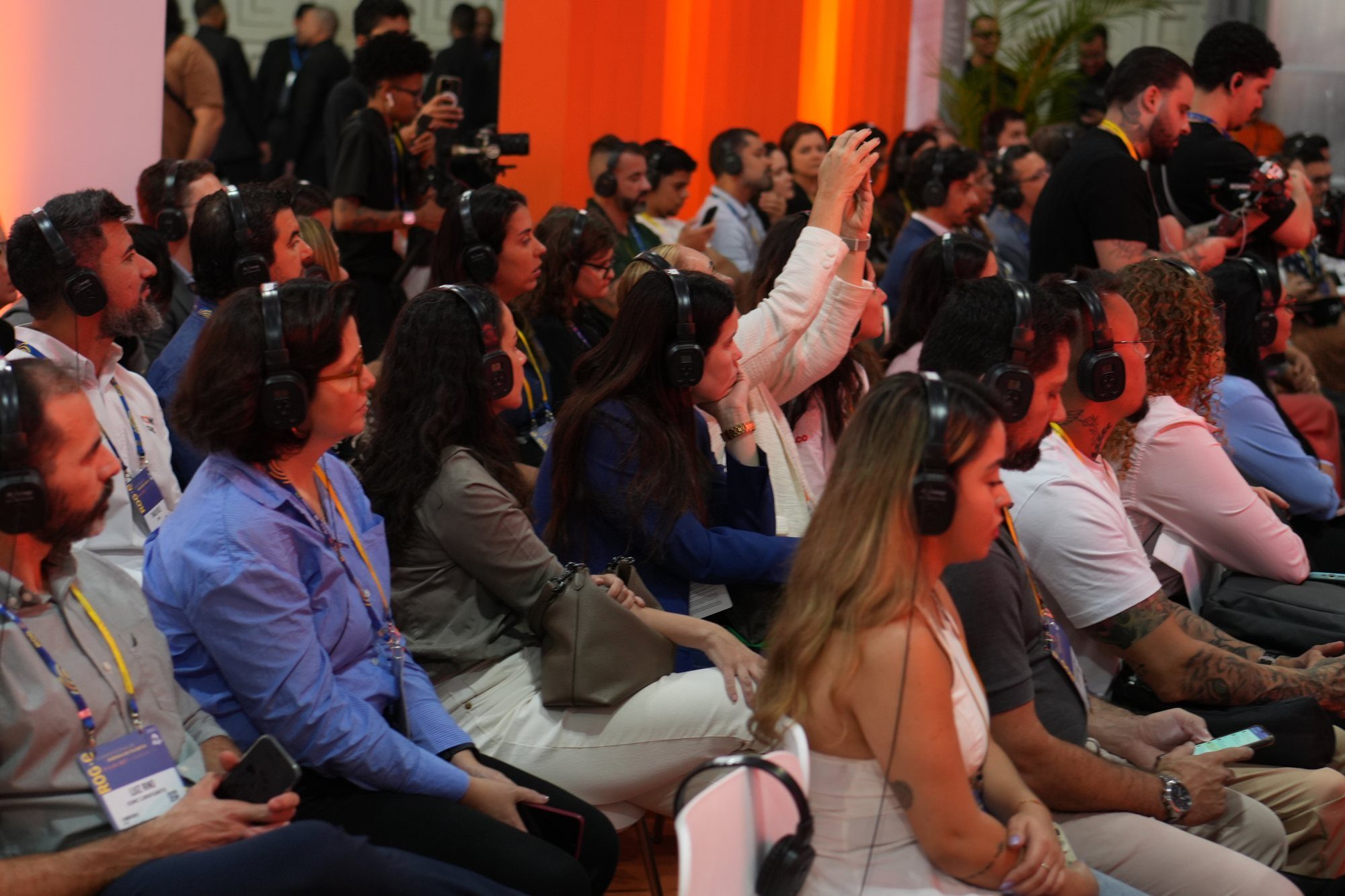Público acompanhando o painel com fones de tradução